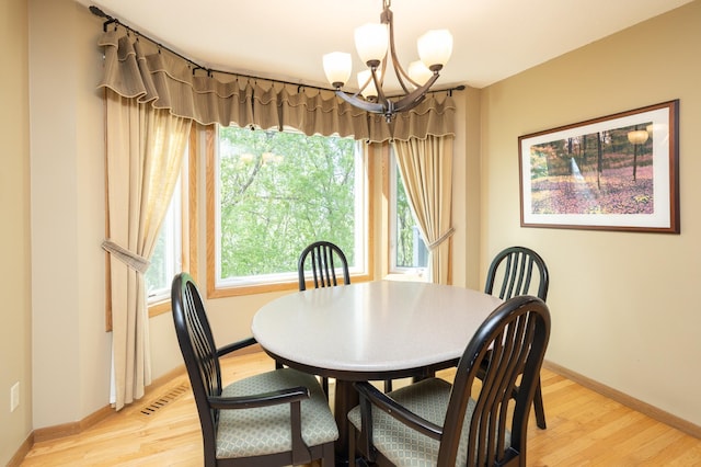 dining area featuring a chandelier, light wood-style floors, and baseboards