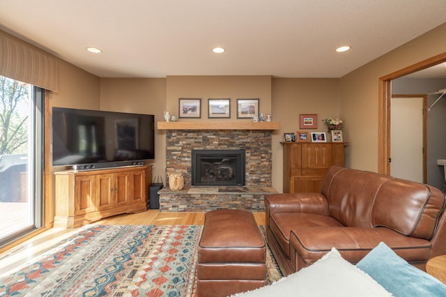 living area with wood finished floors, a stone fireplace, and recessed lighting
