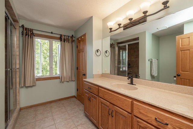 bathroom with baseboards, a stall shower, tile patterned flooring, and vanity