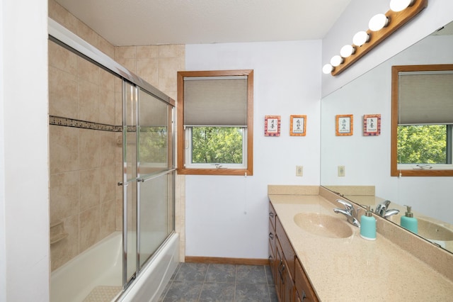 full bathroom with healthy amount of natural light, baseboards, vanity, and bath / shower combo with glass door