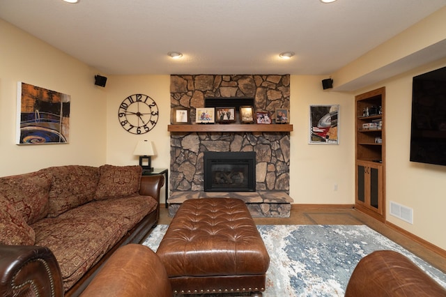 living area featuring a stone fireplace and baseboards