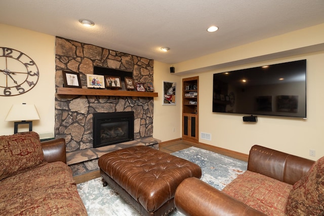living room featuring baseboards and a stone fireplace