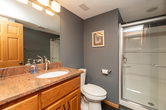 full bath with a shower stall, toilet, vanity, baseboards, and a textured ceiling