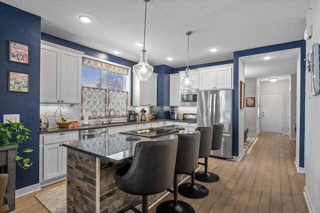 11062 16th St NE, Saint Michael, MN 55376 - kitchen with stainless steel appliances, decorative backsplash, a sink, light wood-style flooring, and a kitchen breakfast bar
