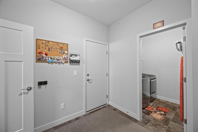 11062 16th St NE, Saint Michael, MN 55376 - foyer entrance with washing machine and clothes dryer, a textured ceiling, baseboards, and dark stone finish floors