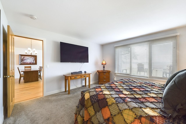 carpeted bedroom featuring a chandelier and baseboards