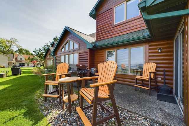 rear view of house with log veneer siding, roof with shingles, a yard, and a patio
