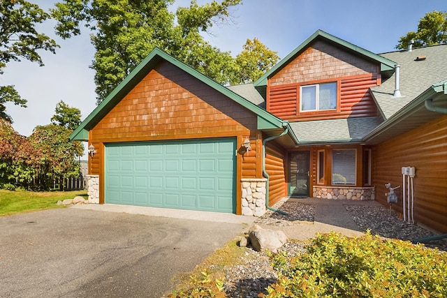 rustic home featuring a shingled roof, driveway, an attached garage, and stone siding