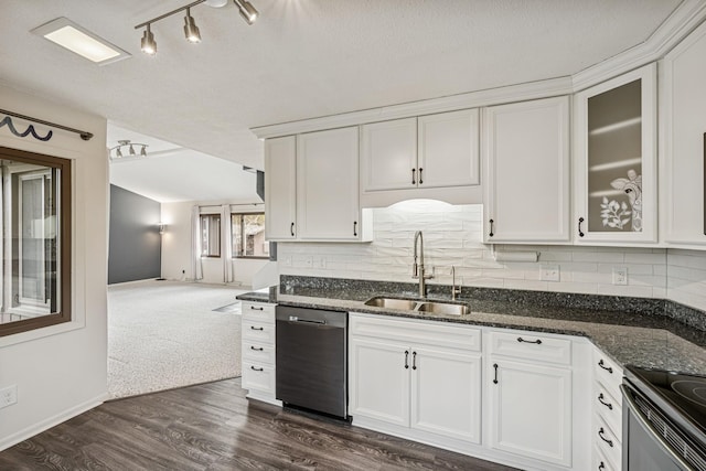 kitchen with dark stone countertops, a sink, stainless steel appliances, white cabinetry, and decorative backsplash