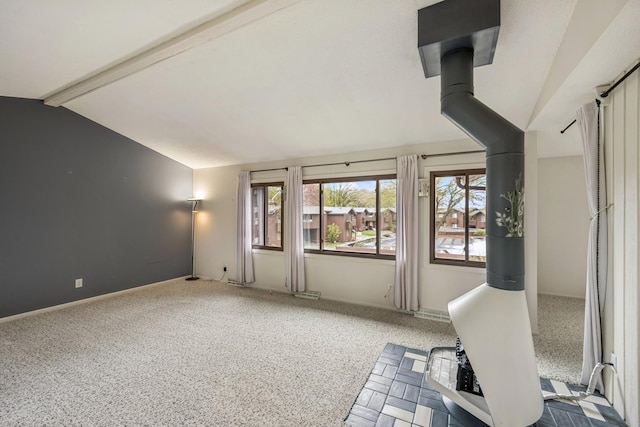 interior space with carpet, baseboards, a wood stove, and vaulted ceiling with beams