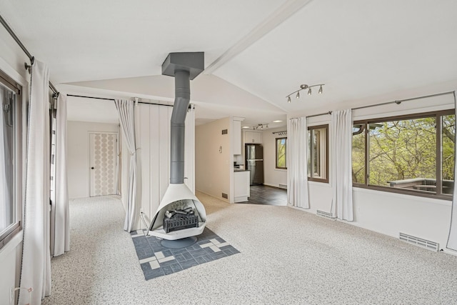 interior space with lofted ceiling, a wood stove, and visible vents