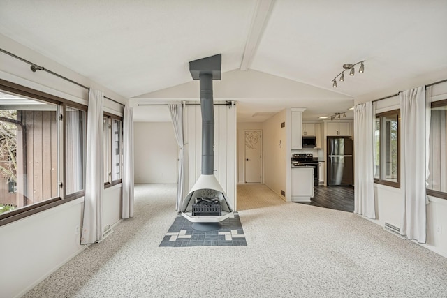 exercise area with a wood stove, plenty of natural light, baseboards, and lofted ceiling