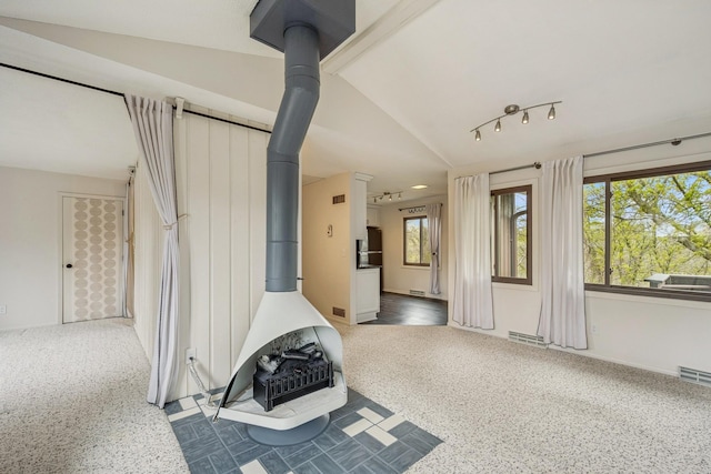 interior space with a wood stove, lofted ceiling, carpet, and visible vents