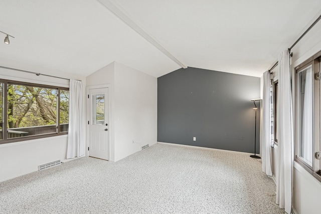 unfurnished room with baseboards, visible vents, and vaulted ceiling with beams