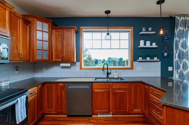 kitchen with stainless steel appliances, a sink, brown cabinetry, glass insert cabinets, and dark wood-style flooring