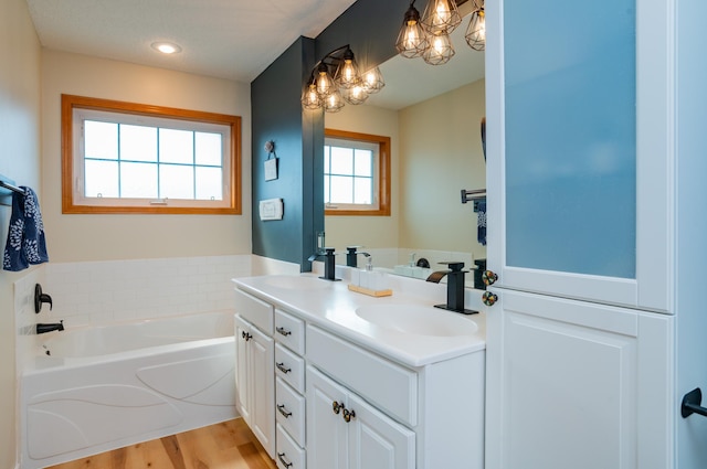 bathroom featuring a chandelier, double vanity, a bath, and wood finished floors