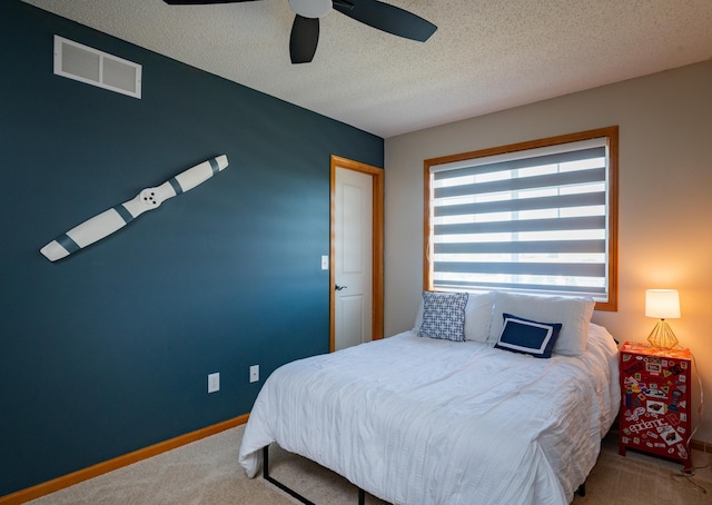 carpeted bedroom featuring baseboards, ceiling fan, and a textured ceiling