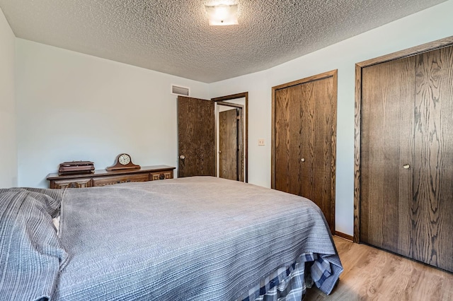 792 Gramsie Rd, Shoreview, MN 55126 - bedroom featuring multiple closets, light wood-style floors, and a textured ceiling