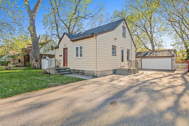 view of front of home featuring driveway, an outdoor structure, a front lawn, and fence