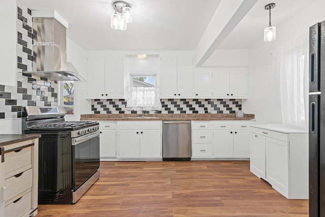 kitchen with backsplash, a wealth of natural light, appliances with stainless steel finishes, and wall chimney exhaust hood