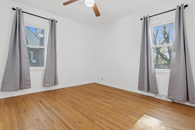 spare room featuring baseboards, light wood-style floors, and ceiling fan