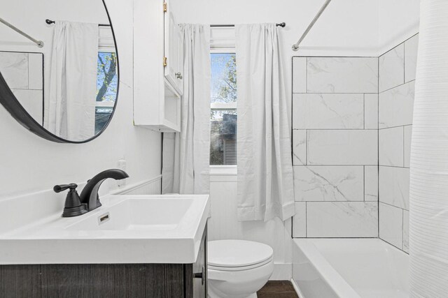 full bath with toilet, shower / tub combo with curtain, and a sink