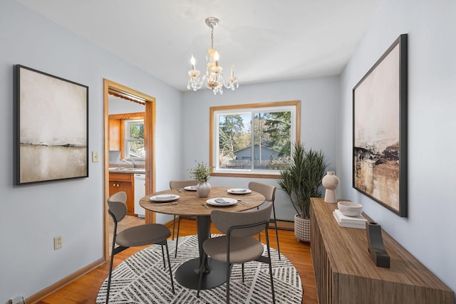 600 Mclean St, Mora, MN 55051 - dining area with light wood-style floors, a chandelier, a baseboard heating unit, and baseboards