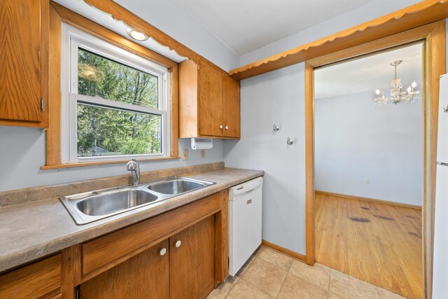 600 Mclean St, Mora, MN 55051 - kitchen featuring dishwasher, a sink, brown cabinets, light countertops, and a chandelier
