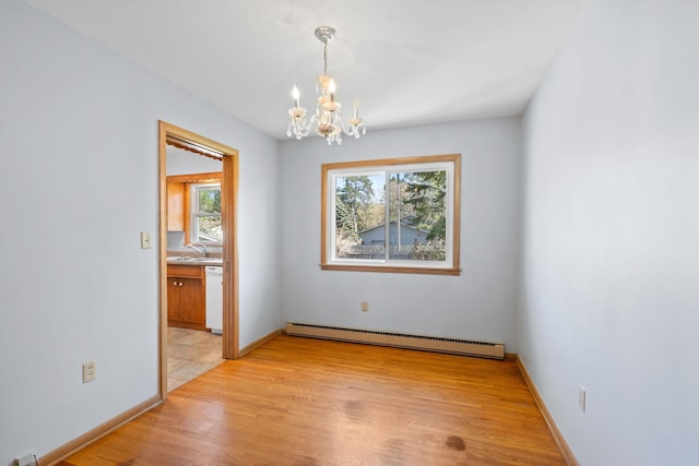 600 Mclean St, Mora, MN 55051 - unfurnished dining area featuring baseboard heating, a chandelier, a sink, light wood-type flooring, and baseboards