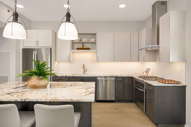 kitchen with stainless steel appliances, a sink, light wood finished floors, wall chimney range hood, and open shelves