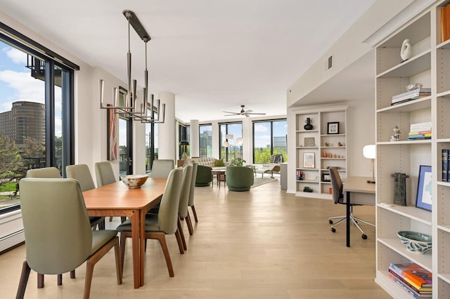 dining room featuring light wood-style flooring, a desk, a ceiling fan, and a wall of windows