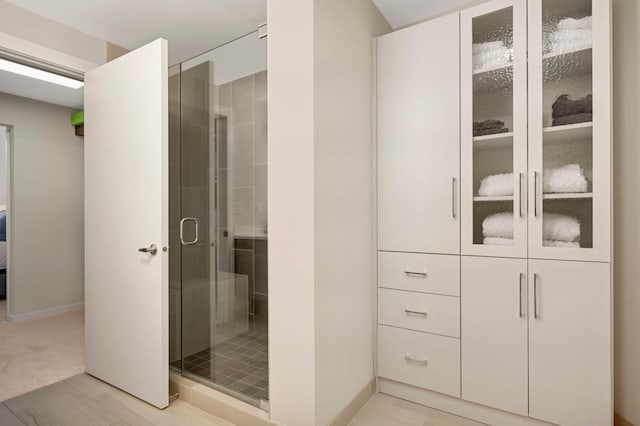 bathroom with a shower stall and baseboards