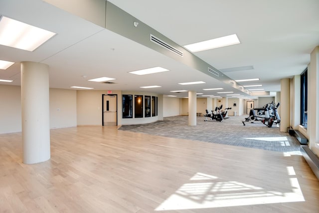 workout area with light wood finished floors and ornate columns