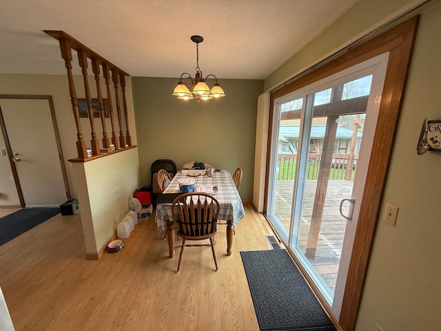 dining area with baseboards, a notable chandelier, light wood finished floors, and visible vents