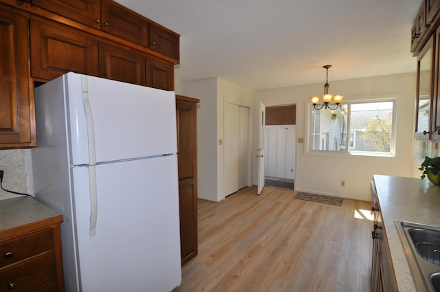 811 Pleasant Ave S, Park Rapids, MN 56470 - kitchen with freestanding refrigerator, a notable chandelier, baseboards, a sink, and light wood-type flooring