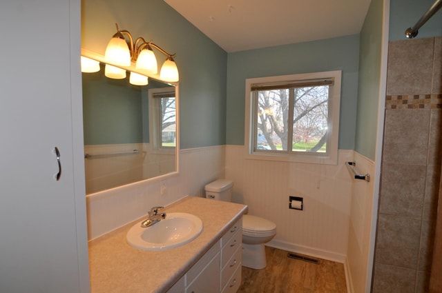 811 Pleasant Ave S, Park Rapids, MN 56470 - bathroom with toilet, visible vents, vanity, a wainscoted wall, and wood finished floors