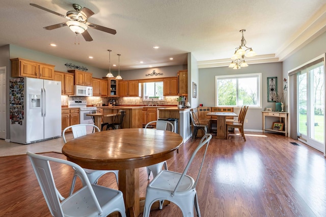 dining area with healthy amount of natural light, a chandelier, light wood-style floors, a ceiling fan, and recessed lighting