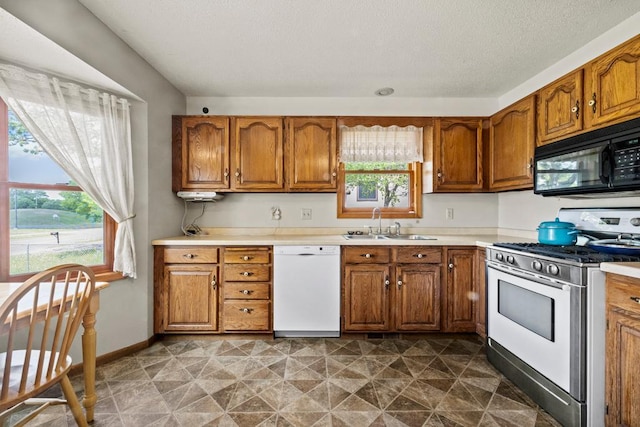 12201 Olive St NW, Coon Rapids, MN 55448 - kitchen with black microwave, gas range, dishwasher, a sink, and brown cabinets