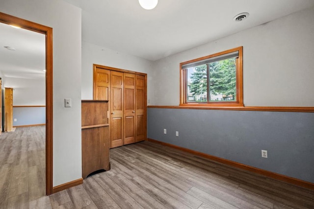 12201 Olive St NW, Coon Rapids, MN 55448 - unfurnished bedroom with wood finished floors, baseboards, and a closet