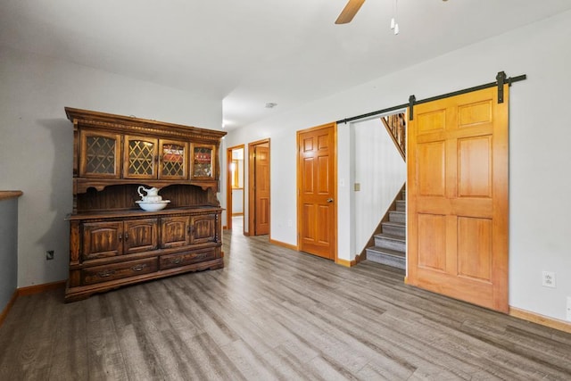 12201 Olive St NW, Coon Rapids, MN 55448 - unfurnished room with wood finished floors, baseboards, a ceiling fan, and a barn door