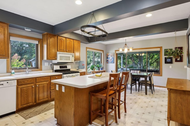 kitchen featuring a wealth of natural light, light floors, a sink, and white appliances