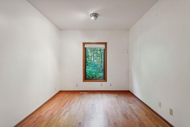 spare room featuring baseboards, light wood finished floors, and visible vents