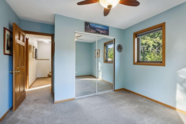 unfurnished bedroom with carpet, a closet, baseboards, and ceiling fan