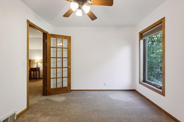 carpeted empty room with a ceiling fan, baseboards, and visible vents