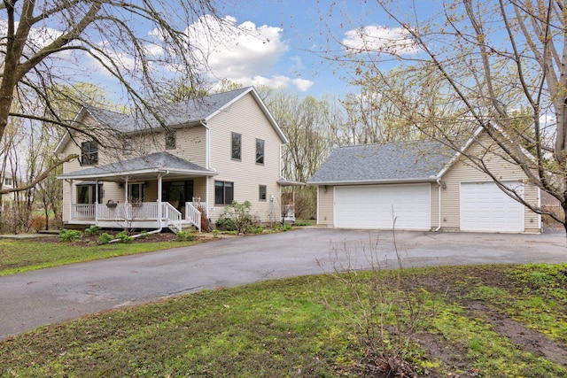 traditional home with covered porch, an outbuilding, and aphalt driveway