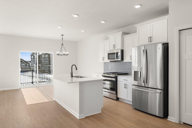 6738 Wildflower Way, Minnetrista, MN 55331 - kitchen with appliances with stainless steel finishes, a sink, light wood finished floors, a center island with sink, and white cabinetry
