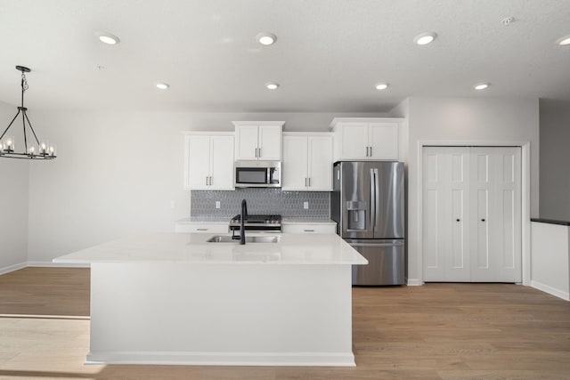 6738 Wildflower Way, Minnetrista, MN 55331 - kitchen with appliances with stainless steel finishes, decorative backsplash, white cabinetry, an island with sink, and a sink