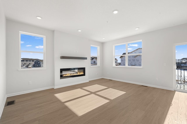 6738 Wildflower Way, Minnetrista, MN 55331 - unfurnished living room with wood finished floors, baseboards, a glass covered fireplace, and recessed lighting