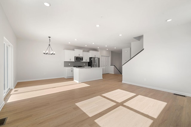 6738 Wildflower Way, Minnetrista, MN 55331 - unfurnished living room with baseboards, light wood-style floors, recessed lighting, and a chandelier