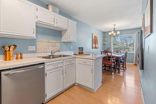 kitchen featuring a sink, dishwasher, light wood finished floors, a chandelier, and white cabinets